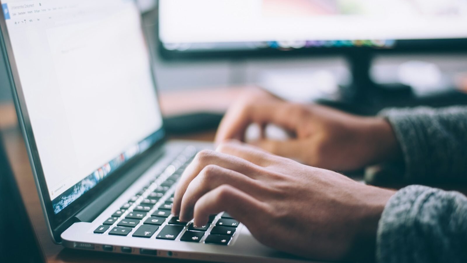 Hands typing on a laptop keyboard