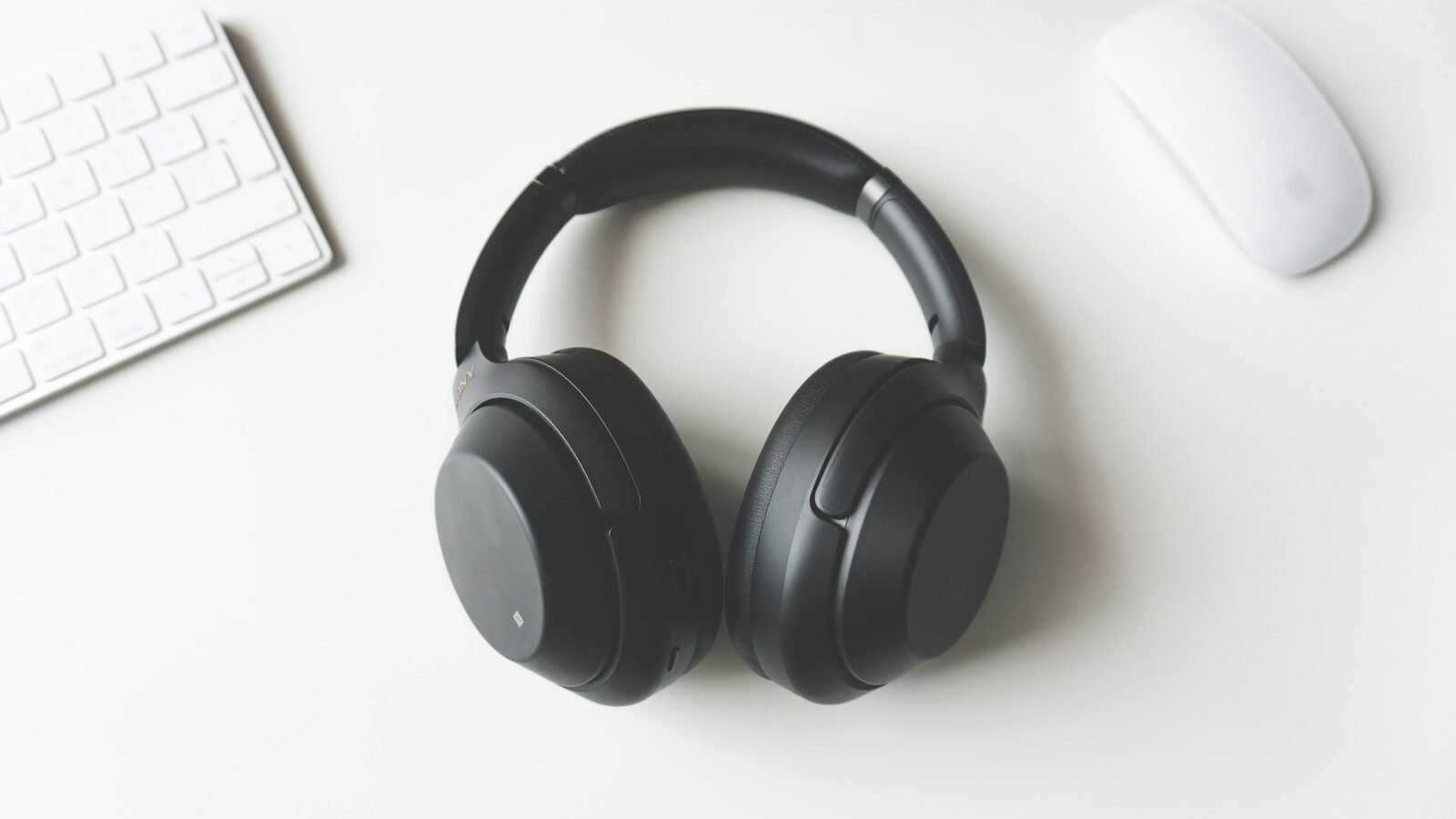 Over-ear headphones resting on a desk beside a laptop